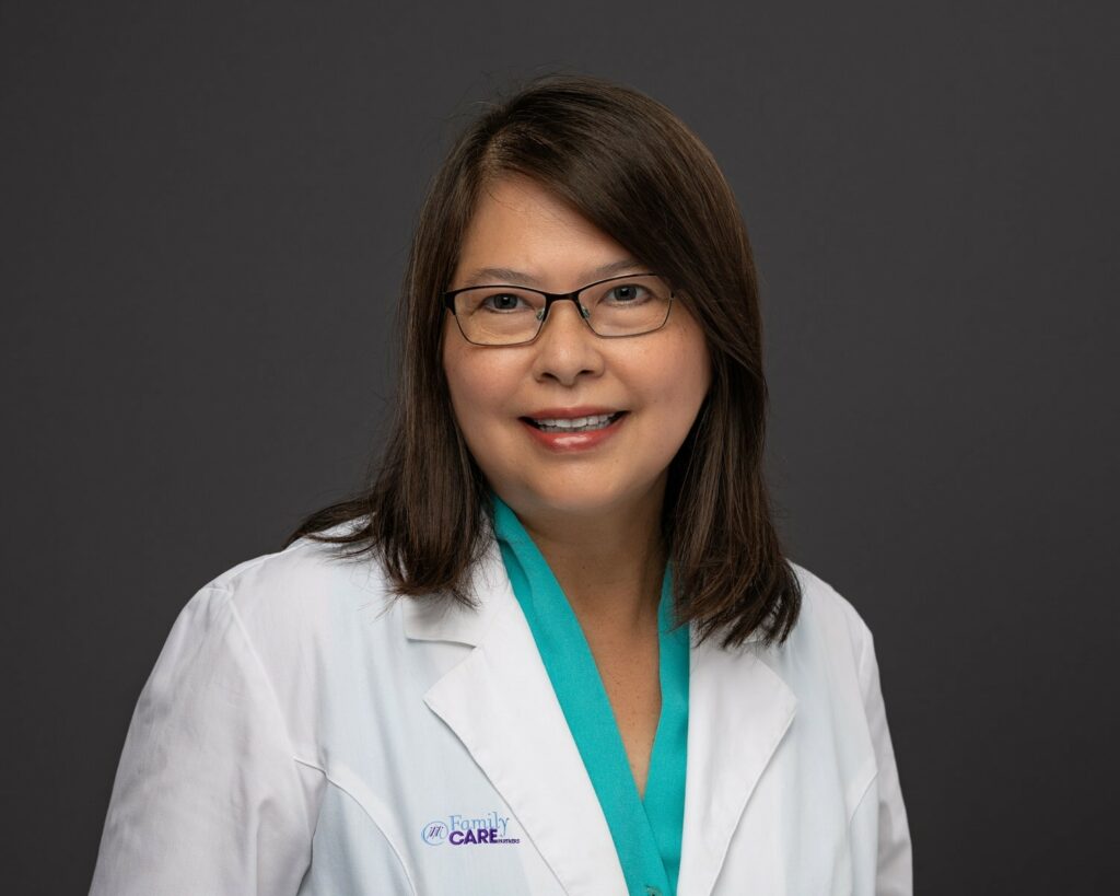 brown haired lady with glasses smiling in a lab coat