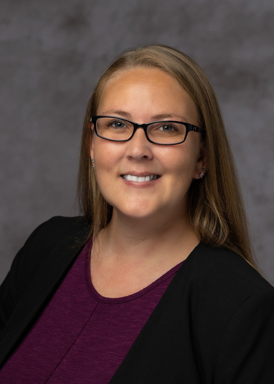 lady with blonde hair and glasses smiling in business casual