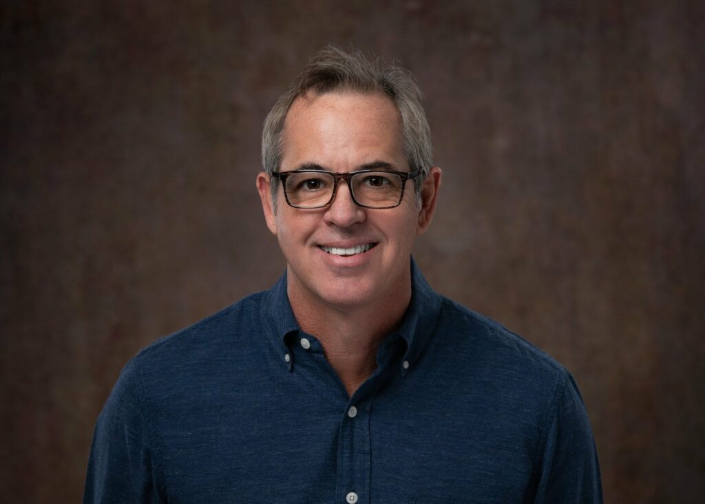 man with glasses in a blue button down smiling