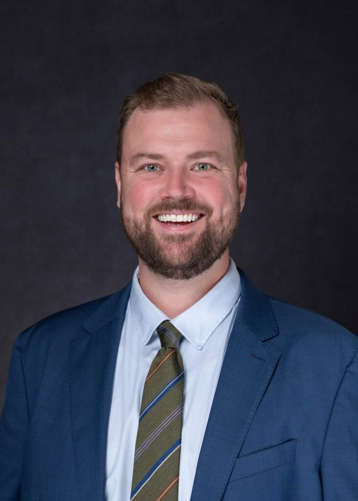 bearded business executive in light blue shirt with tie and jacket