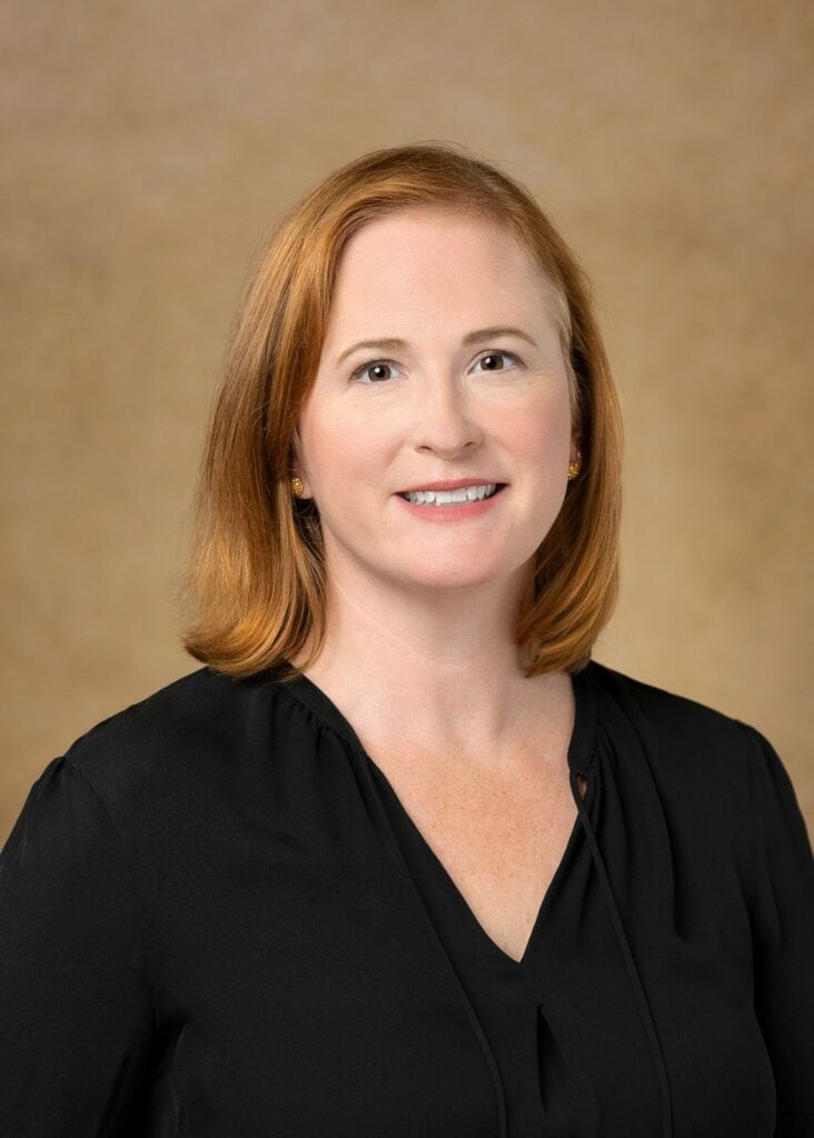 red-headed lady in a dark shirt posing for a corporate headshot