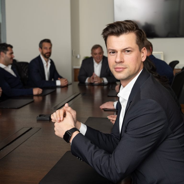 Executive with hands together in boardroom for meeting.