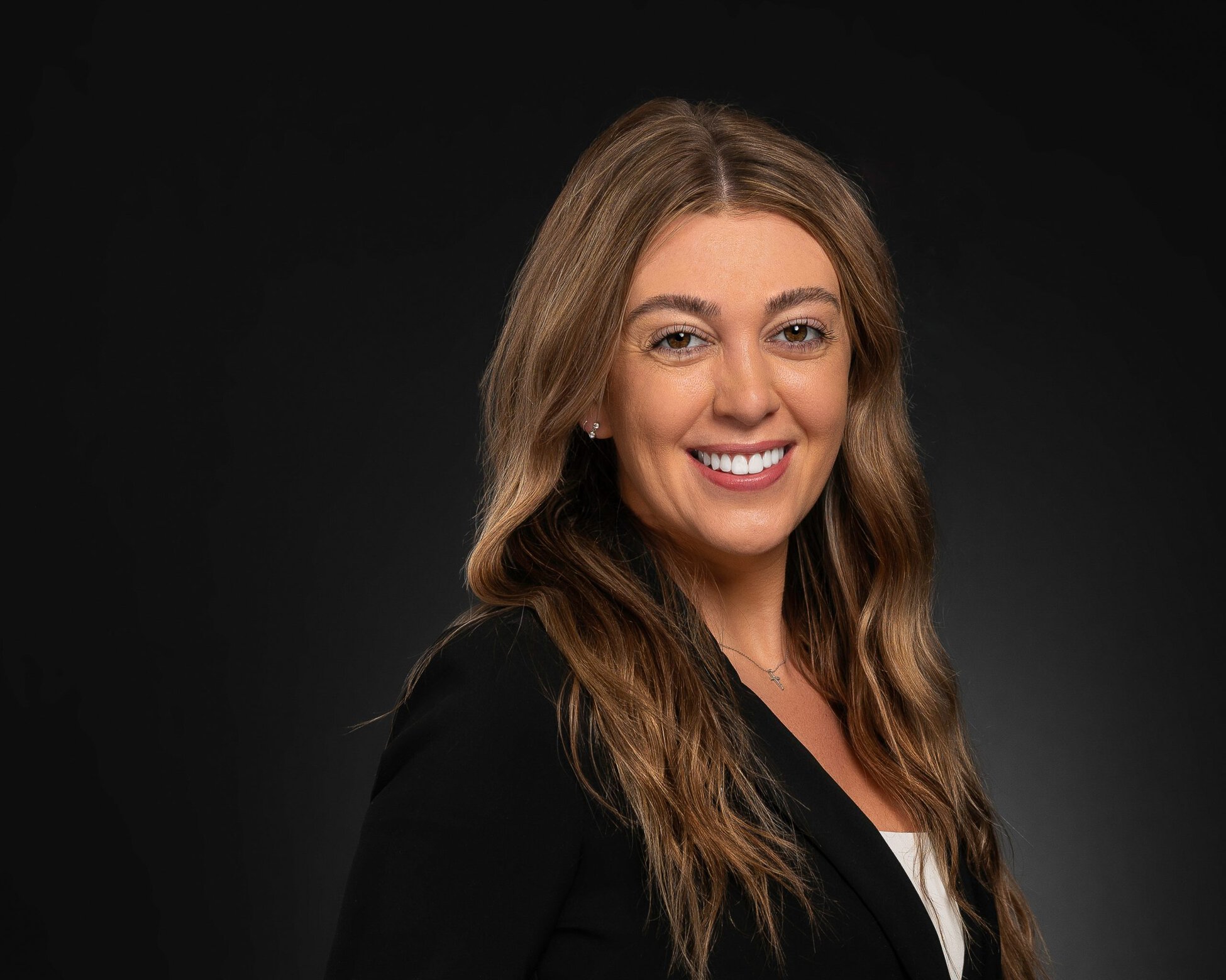 Commercial Real Estate Consultant looking at camera and smiling. Wearing a white top and black blazer for this business formal professional headshot. 
