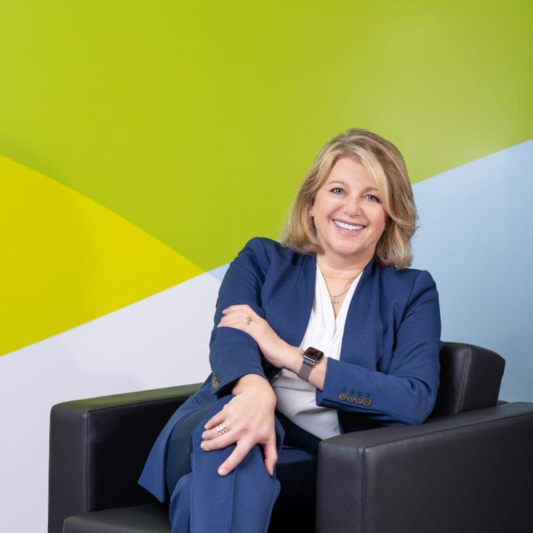 Corporate officer smiling while looking at camera for a business portrait in the reception area of her company.