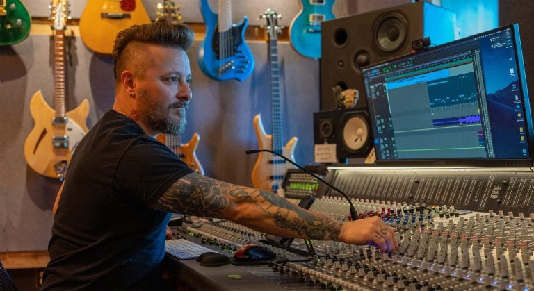 Recording artist at mixing desk adjusting the dials while being photographed for a corporate lifestyles photo.