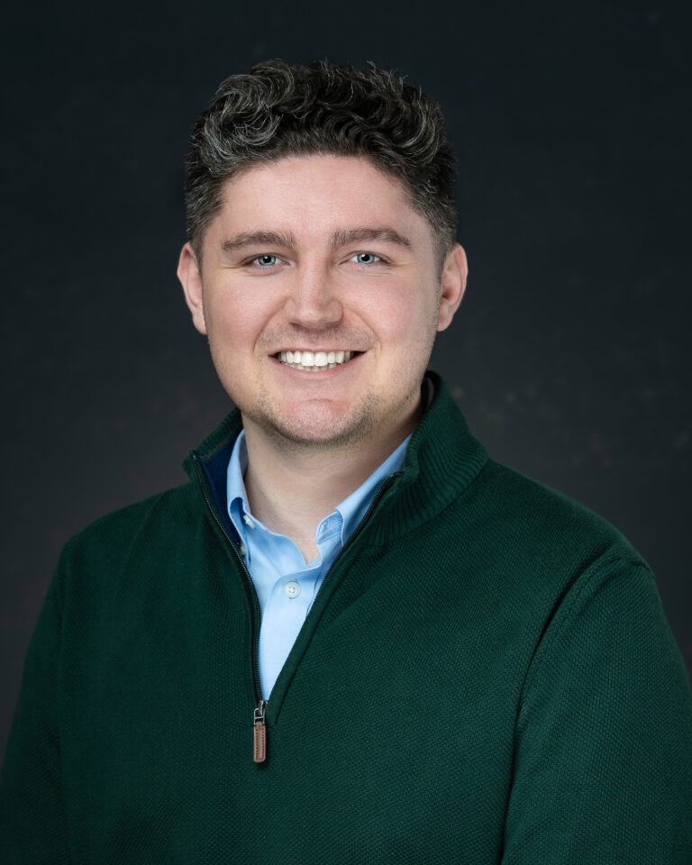 Man got a conference headshots in Jacksonville wearing green sweater and smiling.