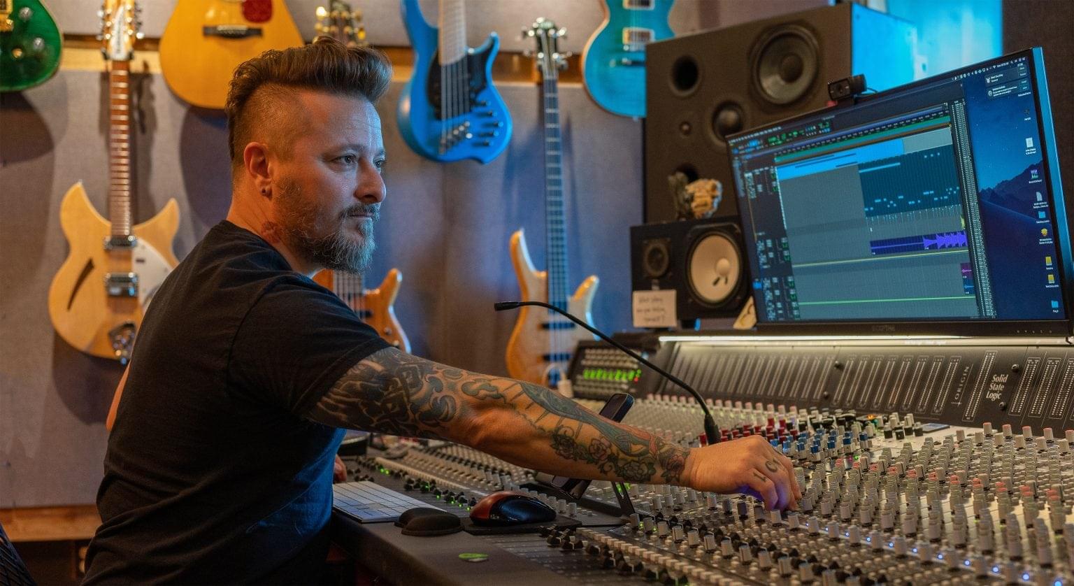 Corporate Lifestyle photography. Recording artist at mixing desk adjusting the dials while being photographed for a corporate lifestyles photo.